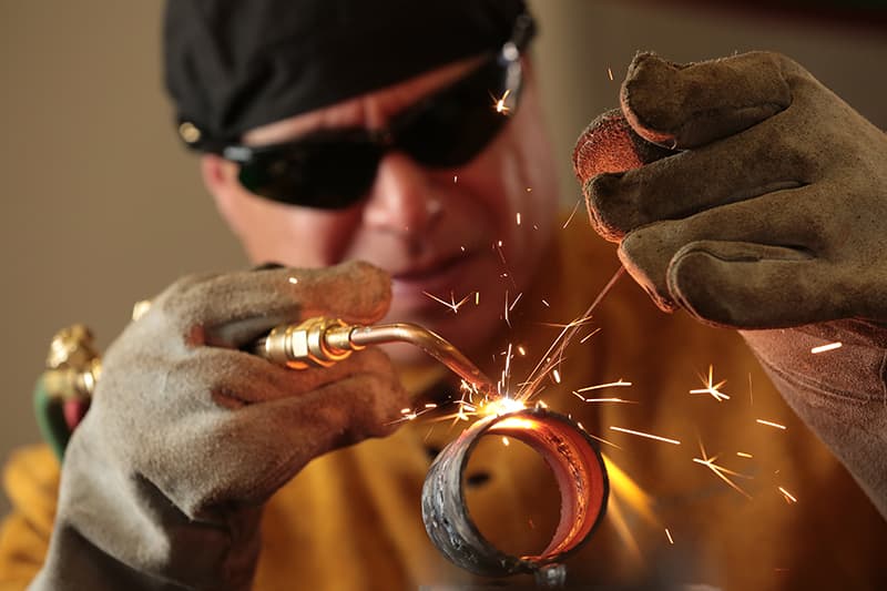 A welding professor at Summit College working with a torch