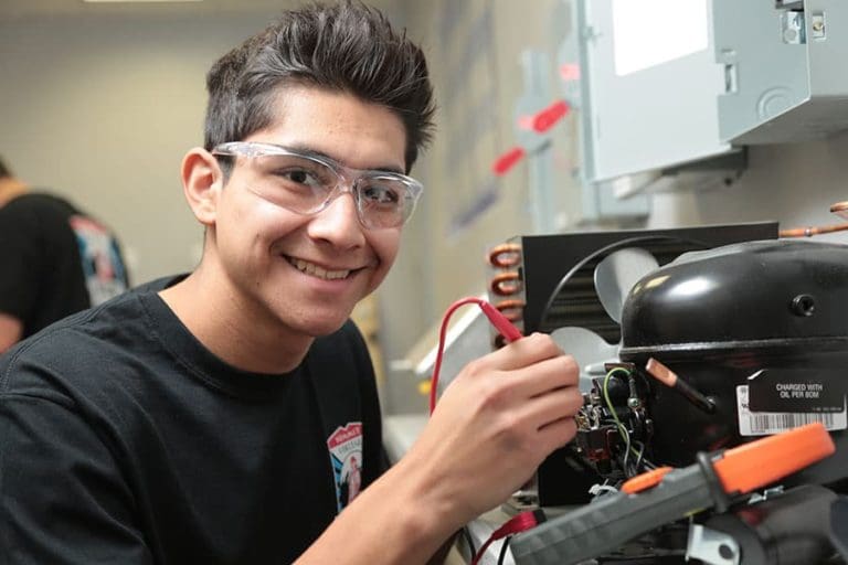 A Summit College HVAC student working on a real air conditioner motor.