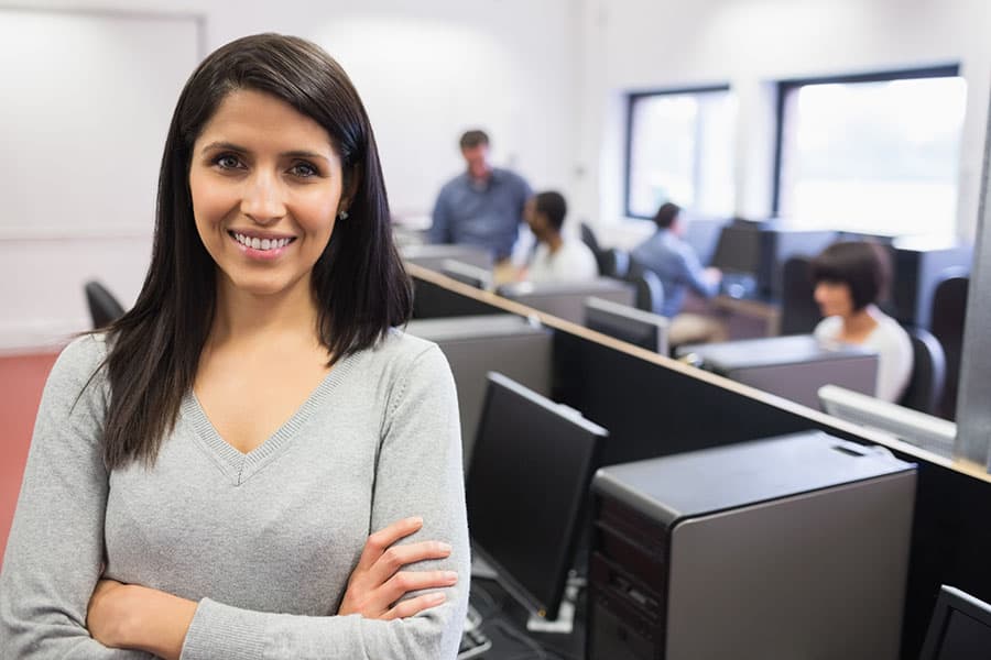 A smiling young woman in a business and computers classroom.